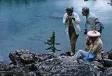 Three tourists photographing a marmot on a trail along the edge of Lake O'Hara August, 1963