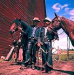 Deux cowboys debout à côté de leurs chevaux, les rênes à la main 1952