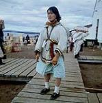 Femme [Tikisa (Mikijuk) Takpannie] participant au déchargement d'une barge de la Compagnie de la Baie d'Hudson à Apex, baie Frobisher, T.N.-O., [Iqaluit (anciennement baie Frobisher), Nunavut] [between June-September, 1960].