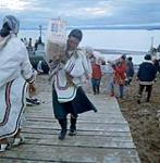 Femmes [Susie Kaivaluaqjuk] déchargeant des sacs de sucre d'une barge de la Compagnie de la Baie d'Hudson à Apex, baie Frobisher, T.N.-O., [Iqaluit (anciennement baie Frobisher), Nunavut] [between June-September, 1960].