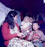 Hilda Irish making dolls with her three children, Aklavik, N.W.T. July 17, 1956.
