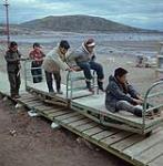 Garçons participant au déchargement d'une barge de la Compagnie de la Baie d'Hudson à Apex, baie Frobisher, T.N.-O., [Iqaluit (anciennement baie Frobisher), Nunavut] [entre juin-septembre 1960].
