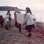 Femmes participant au déchargement d'une barge de la Compagnie de la Baie d'Hudson à Apex, baie Frobisher, T.N.-O., [Iqaluit (anciennement baie Frobisher), Nunavut] [between June-September, 1960].