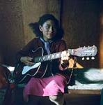 Woman [Jeanette Kangigana] playing the guitar, Richards Island, Inuvik, N.W.T. juillet 1956.