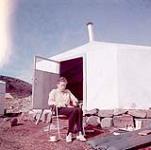 Barbara Hinds eating outside, Cape Dorset, Nunavut [between June-September, 1960].