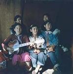 Cinq femmes [Femme en veste bleue est Jean Kupok] en train de chanter et une jouant de la guitare, île Richards, Inuvik, T.N.-O. juillet 1956.