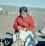 Femme en train de coudre à l'extérieur, baie Frobisher, T.N.-O., [Iqaluit (anciennement baie Frobisher), Nunavut] [entre 17 juin-24 août 1960].