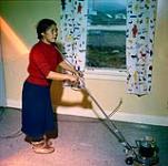 Ikhalu utilisant une polisseuse électrique à plancher dans la maison de James et Alma Houston, Cape Dorset, Nunavut [entre juin-septembre 1960].
