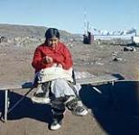 Woman sewing outside, Frobisher Bay, N.W.T., [Iqaluit (formerly Frobisher Bay), Nunavut] [entre 17 juin-24 août 1960].