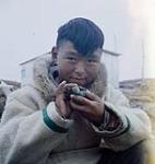 Ten year-old sculptor Teevee holding a miniature seal, Cape Dorset, Nunavut [entre juin-septembre 1960].