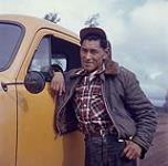 Conducteur de camion inuit appuyé contre son camion jaune [Alex Harley] [ca. 1955-1963]