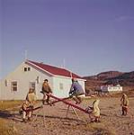 Children playing on seesaw, Cape Dorset, Baffin Island. July 1961