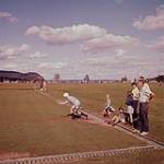 [A woman throwing a ball while men and children watch on a lawn bowling field, New Brunswick] August 1956
