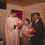 The Wincree twins are christened in their home by Rev. Leslie Corness, the local Anglican missionary at Frobisher Bay, N.W.T. mai 1958.