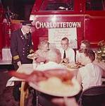 [Fireman standing with men and women seated at table for the Charlottetown fireman's lobster supper] 28 juin 1961