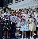 An ethnic study as well as the children at Luxton School taking part in the flag-raising ceremonies held on closing day. Winnipeg, Manitoba. 01 juillet 1961