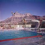 Some high diving taking place in the Waterton Lakes National Park swimming pool, Alberta. Vimy Ridge can be seen in the background. août 1961
