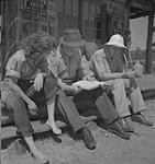 Captain of the clouds (Les chevaliers du ciel), deux hommes et une dame assis à l'extérieur d'un poste de traite. North Bay, Ontario August, 1941