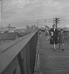 Saskatoon et blé, femmes et filles non identifiées traversant une passerelle [between 1939-1951].