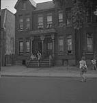 Toronto, scène de rue avec des enfants s'amusant et un groupe assis sur le perron d'une maison [entre 1939-1951].