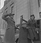 Hôpital Women's College. Une femme non identifiée en uniforme tient la porte et salue une femme non identifiée en uniforme qui sort d'une voiture [between 1939-1951]