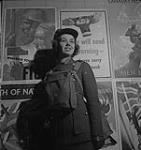 Woman's Air Force, 1940's.   Unidentified Woman in Uniform and Bag on Chest in Front of Canada's New Army Posters [entre 1940-1949]