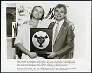 Phil Collins being presented with Ampex's Golden Reel Award for his hit album No Jacket Required. Pictured here from left to right are Phil Collins, who also co-produced the album, and Tony Shields, Ampex Tape Sales Representative [entre 1985-1990]