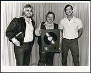 Country artist John Conlee (center) being presented with a gold award for his album "John Conlee's Greatest Hits." Pictured with Conlee are MCA Canada V.P. of Marketing Graham Powers (left) and V.P. of Sales George Burns (right) [between 1983-1984]