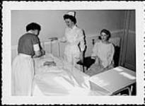 Snap-shot of a young student nurse giving a patient a drink during clinical instruction. Nurses and Nursing. Department of Citizenship and Immigration, Information Division [between 1930-1960]