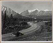 Mile 1021, Alaska Highway, with the snowy peak of Mt. Archibald shining ahead 1949.