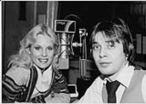 Portrait of Don Jackson of FM / 96 (Montréal) sharing a microphone with Miss August Playmate (Dorothy Stratton) during one of his shows [entre 1980-1990]