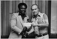 Radio program manager Fred King hands a cheque to the George Reed Foundation from last year's...(?) [entre 1975-1985]