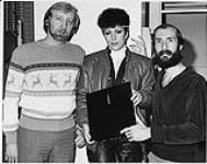 Portrait of CKOC radio's John Novak and Ray Girard with recording artist Rita Johns who stopped by with a clear vinyl edition of her new single She's In Love With Her Radio. Hamilton [between 1981-1987].