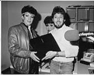 Recording artist Rita Johns presenting a promo copy of her single She's In Love With Her Radio to CFNY-FM personality James Scott [between 1981-1987].