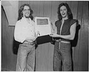 Bond guitarist Ted Trenholm accepts a BMI Certificate of Honour from CJCH's (Halifax) Terry Williams for his composition When You're Up You're Up which put Bond into the charts [ca 1975]