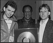 L to R: Kim Cooke (Label Manager), Bill Cosby, and Randy Stark (WEA Vancouver Branch Manager). After performing at Expo in Vancouver, Cosby was presented with a Gold album for his earlier work 1986