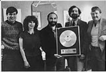 WEA Music of Canada presenting a Platinum Award to CKIK-FM for their contribution in breaking Men Without Hats 'Rhythm of Youth' album. L to R: David Kitching (WEA Calgary), Jamie Wohl (Music Director, CKIK), Larry Green (WEA National Promotion Manager), Andy Forsythe (PD CKIK), and Alex Clark (WEA, Calgary) [between 1982-1983].