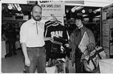 Stewart Duncan (Manager of Sam The Record Man flagship store on Yonge Street, Toronto) and Susan Fulton, grand prize winner of the MCA / Sam The Record Man / CFNY Twelve Days of Christmas contest. The prize was a $1,002.00 shopping spree at Sam's Yonge Street location [entre 1980-1990]