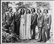 Portrait de presse du groupe The Family Brown. Les hommes portent un complet-cravate et les femmes, une robe à motif floral [entre 1972-1980].