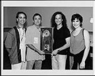 Les membres du personnel de BMG félicitent l'artiste exécutant d'Arista Kenny G pour le succès de son dernier album, « The Moment », certifié double platine [ca 1997].