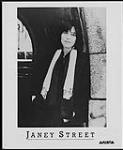Publicity portrait of Janey Street wearing a scarf and standing under a stone arch [entre 1984-1985].