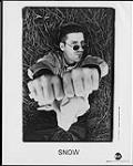 Publicity portrait of Snow lying in the grass with his hands raised in front of him 1996