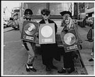 The Thompson Twins holding Gold album awards for "Into The Gap" in Toronto - (left to right) Joe Leeway, Tom Bailey, Alannah Currie [ca. 1984].