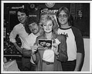 Bonnie Tyler holding a photo of Brad Jones' (CHUM Music Director) dogs - Bonnie and Tyler - and standing with Brad Jones, Dave Deeley at left (CBS-Columbia Marketing Rep) and Al Trickey at right (CHUM Music Librarian) [entre 1983-1988].