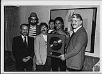 Jermaine Jackson receiving a gold album award at the Olympic Stadium, Montreal: (l to r) Derek Steede (Product Manager, PolyGram), Bob Ansell (VP, Promotion & Media Relations, Polygram), Alain Martineau (Promotion, Polygram), Bill St-Georges (Promotion Manager, Polygram), Jermaine Jackson, Dieter, Radecki (VP and GM, Polygram) [ca. 1984].