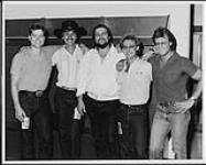Waylon Jennings posing with members of RCA Calgary before a concert at the Olympic Saddledome, Calgary: (l to r) Kevin Roe (Sales), Terry Carson (Branch Manager), Waylon Jennings, Mike Pleau (Promotion), Bryan Boyce (Sales) [between 1980-1985].