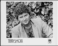 Press portrait of Terry Jacks in front of a hedge [between 1983-1989].