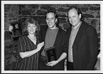 Country sensation Charlie Major displays two more #1 plaques received from SOCAN for "(I Do It) For the Money" (No. 1 RPM, October 1995) and "Tell Me Something I Don't Know" (No. 1 The Record, March, 1996). SOCAN's Lynne Foster and Kent Sturgeon presented the plaques to Charlie at a special dinner in Nashville on April 17, 1996 17 avril 1996