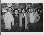 Quatre hommes de l'industrie de la musique réunis devant des photos de stampede [between 1982-1990].