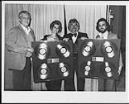 Kenny Rogers gets assistance from his wife Marianne, Bob Rowe and David Munns, holding up his awards at the 1980 Grammys [ca. 1980].